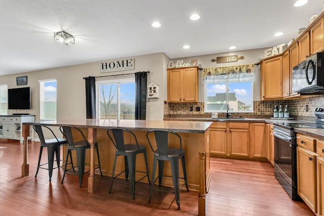 kitchen with sink, a kitchen breakfast bar, range with electric cooktop, and a center island