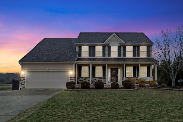 view of front facade with a garage, a porch, and a yard