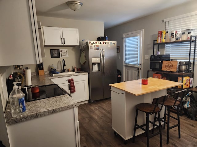 kitchen with stainless steel refrigerator with ice dispenser, a kitchen bar, sink, white cabinetry, and dark hardwood / wood-style flooring