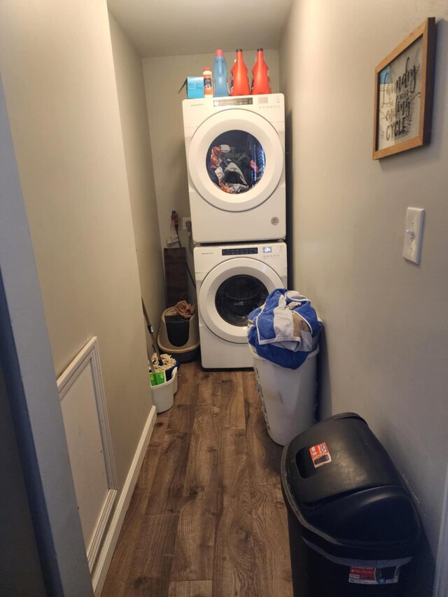 laundry area featuring stacked washer / dryer and dark hardwood / wood-style flooring