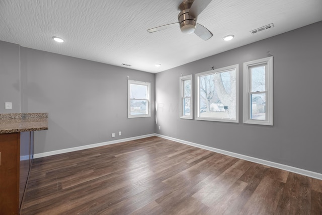 empty room featuring ceiling fan, dark hardwood / wood-style floors, and a textured ceiling