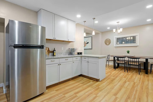 kitchen featuring stainless steel fridge, kitchen peninsula, light wood-type flooring, and white cabinets