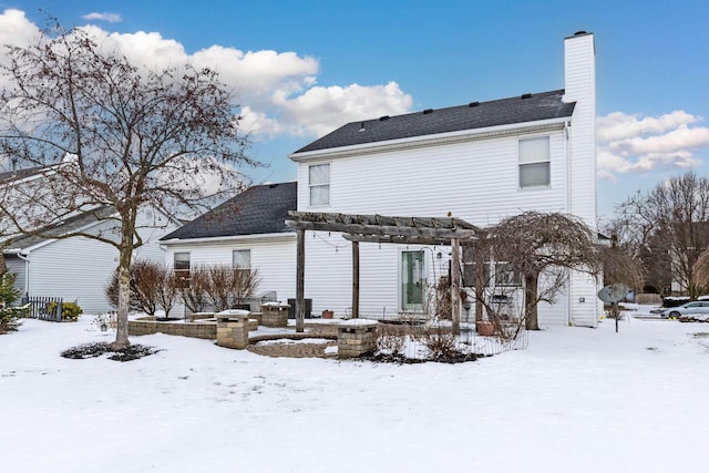 snow covered rear of property with a chimney