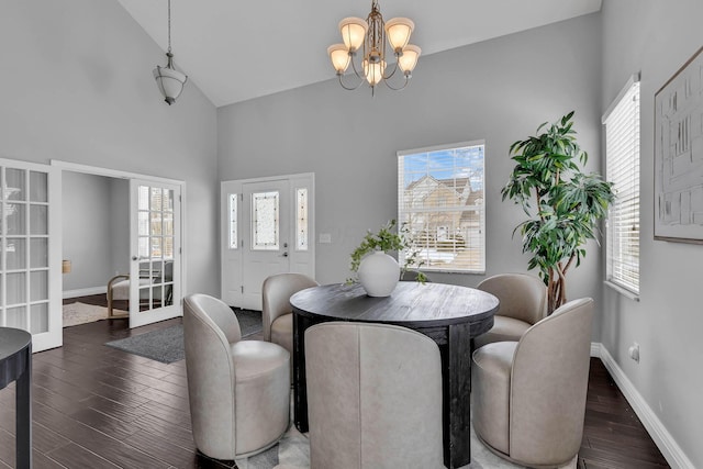 dining space with baseboards, dark wood-type flooring, french doors, high vaulted ceiling, and a notable chandelier