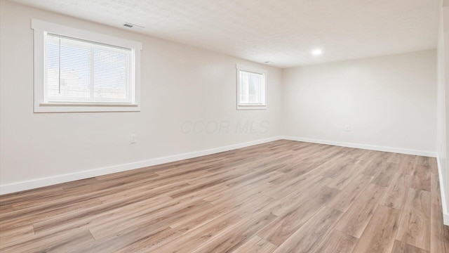 empty room featuring a textured ceiling and light wood-type flooring