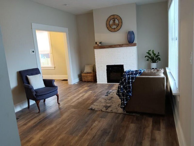 living room with a brick fireplace and dark hardwood / wood-style flooring