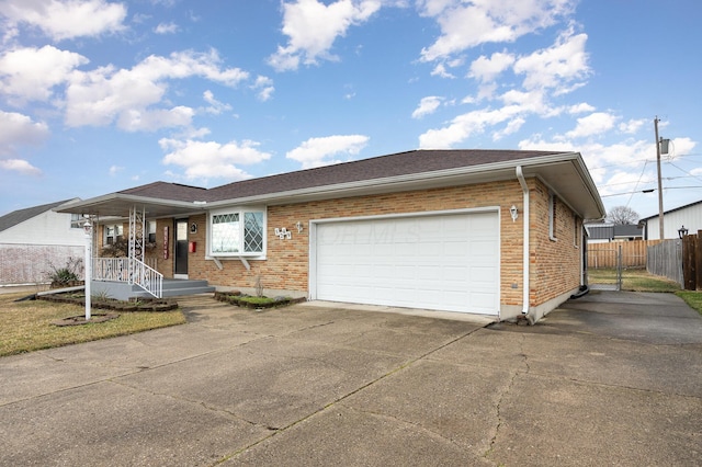 single story home featuring a garage, driveway, brick siding, and fence