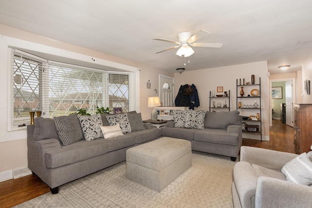 living area featuring baseboards, ceiling fan, visible vents, and wood finished floors