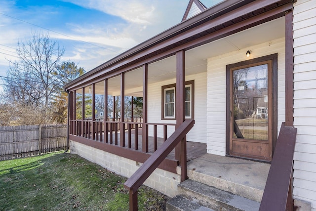 entrance to property with covered porch and fence