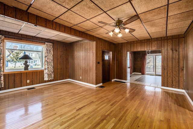 foyer entrance featuring wooden walls, wood finished floors, a ceiling fan, and a healthy amount of sunlight