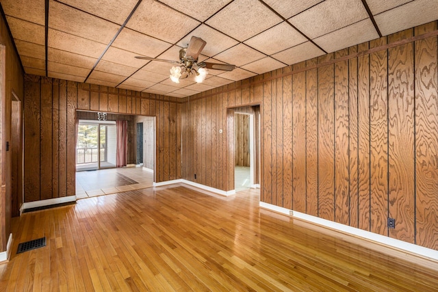 unfurnished room featuring wood walls, light wood-style flooring, and visible vents