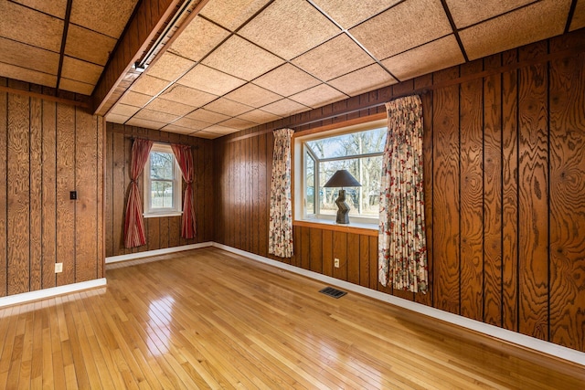 spare room featuring visible vents, baseboards, and wood finished floors