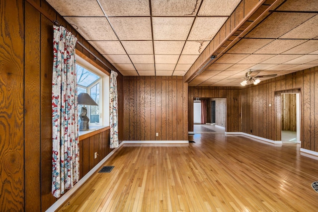 spare room with visible vents, wooden walls, and wood finished floors