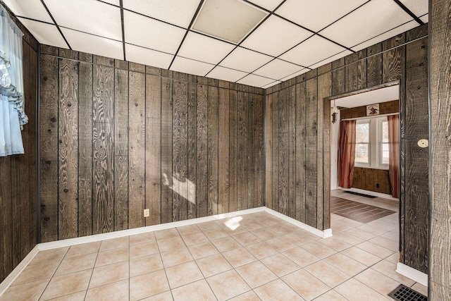 unfurnished room with visible vents, wood walls, and light tile patterned floors