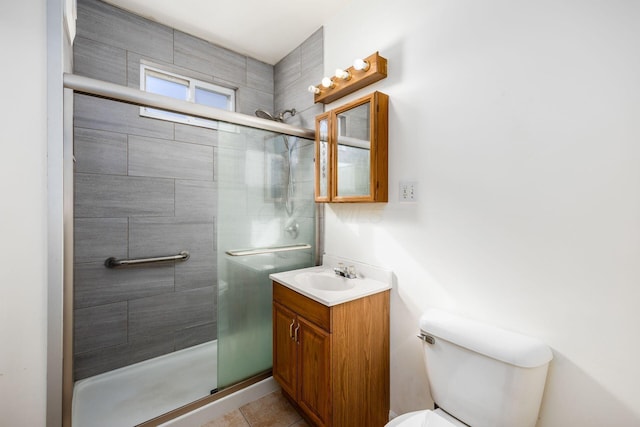 bathroom with toilet, tile patterned floors, a shower stall, and vanity