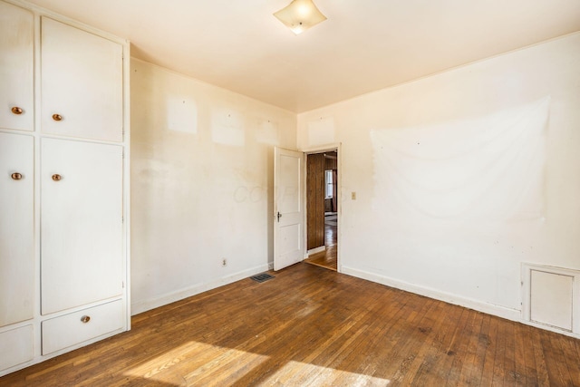 unfurnished bedroom featuring visible vents, dark wood finished floors, and baseboards