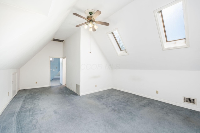 additional living space with vaulted ceiling with skylight, visible vents, and dark carpet