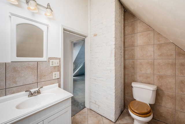 half bath featuring toilet, tile patterned floors, vaulted ceiling, vanity, and tile walls