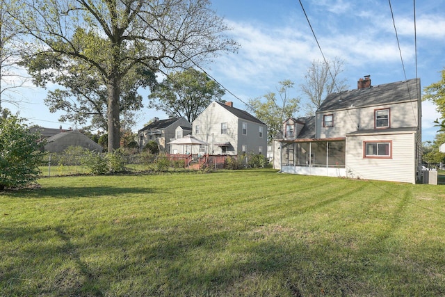 view of yard featuring central air condition unit, fence, a residential view, and a sunroom