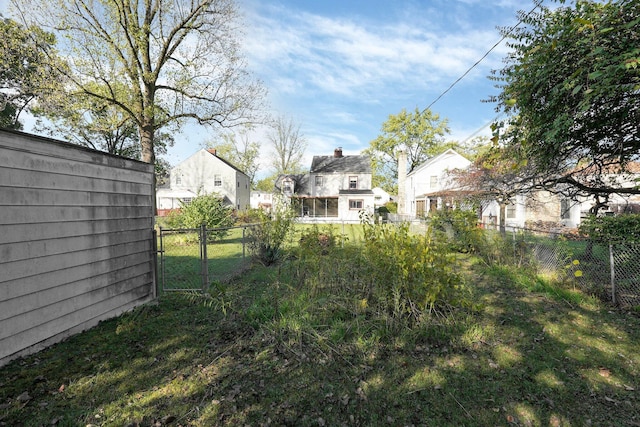 view of yard featuring a gate, fence, and a residential view