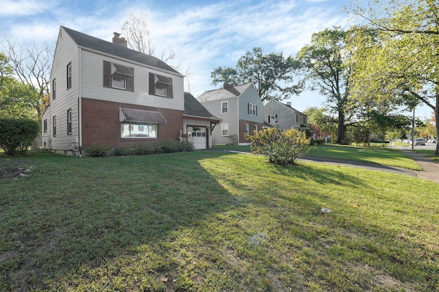 view of front of property featuring a garage, brick siding, a chimney, and a front lawn