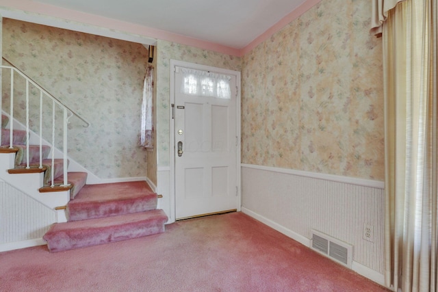 carpeted entrance foyer with stairs, visible vents, wainscoting, and wallpapered walls