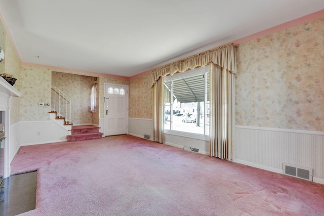 carpeted foyer with wallpapered walls, stairs, visible vents, and wainscoting