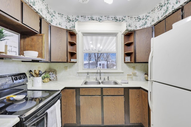 kitchen with electric range, open shelves, a sink, freestanding refrigerator, and light countertops