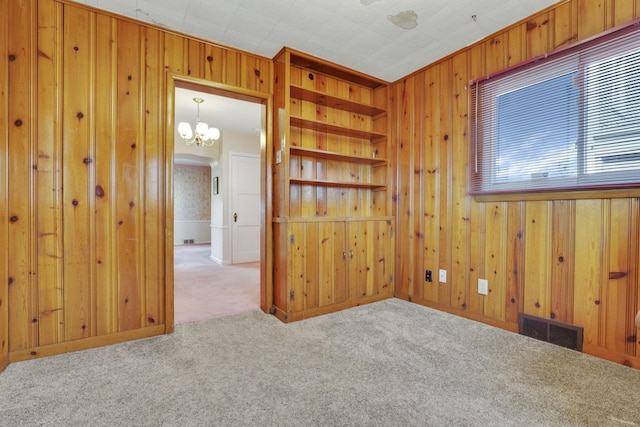 empty room with visible vents, carpet flooring, and wooden walls