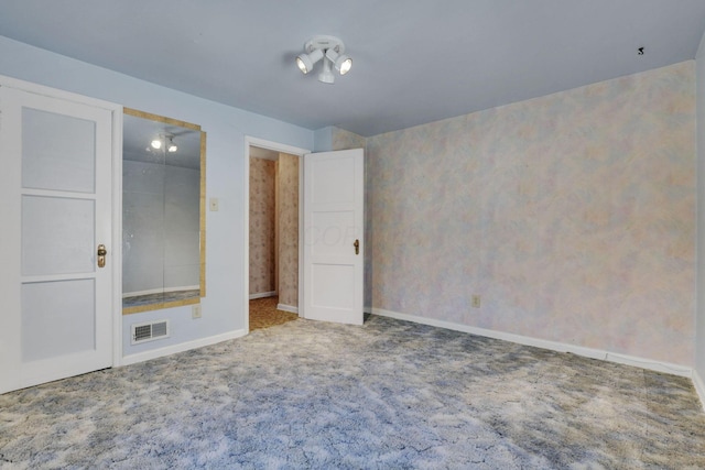 unfurnished bedroom with visible vents, wallpapered walls, baseboards, and carpet floors