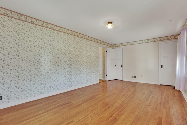 unfurnished room with baseboards, light wood-style flooring, and wallpapered walls