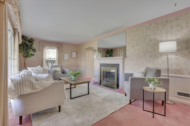 carpeted living room with wallpapered walls, a fireplace with flush hearth, visible vents, and wainscoting