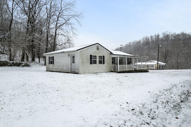 snow covered rear of property with covered porch