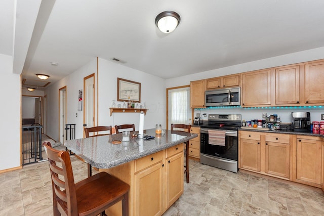 kitchen with stainless steel appliances, a kitchen island, a kitchen breakfast bar, and dark stone counters