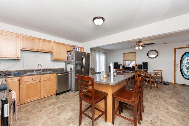 kitchen with ceiling fan, appliances with stainless steel finishes, a kitchen breakfast bar, and sink