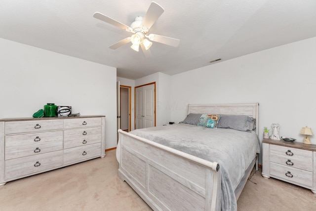 bedroom featuring light colored carpet, ceiling fan, and a closet