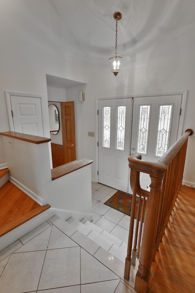 foyer entrance with a chandelier, baseboards, and light tile patterned floors