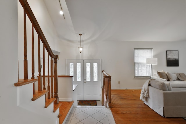 foyer entrance with light wood-type flooring, stairway, and baseboards