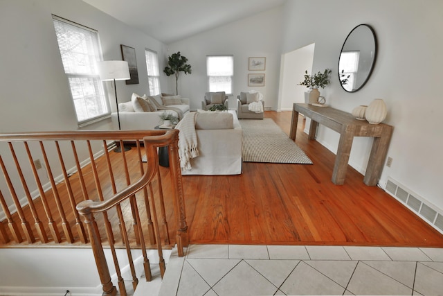 living area with lofted ceiling, baseboards, visible vents, and light tile patterned flooring