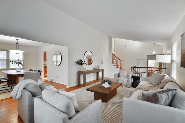 living area featuring lofted ceiling, wood finished floors, stairs, and baseboards