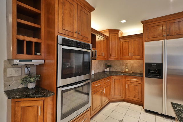 kitchen with light tile patterned flooring, appliances with stainless steel finishes, brown cabinets, dark stone counters, and open shelves