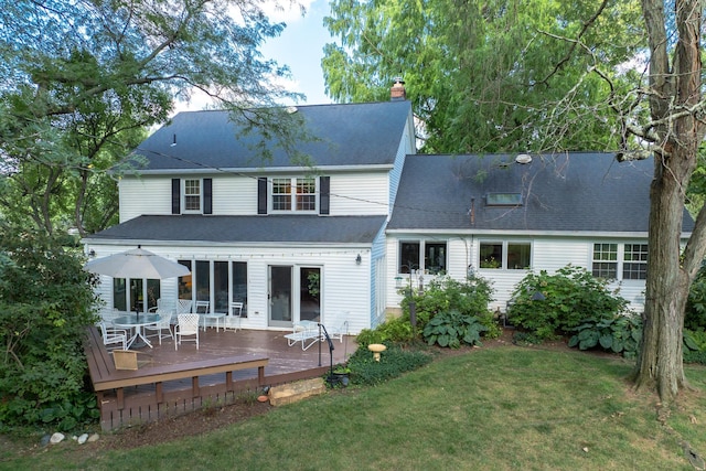 back of property featuring a deck, a lawn, and a chimney