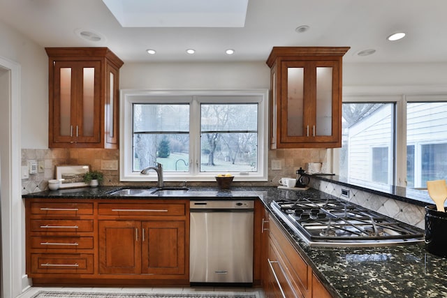 kitchen featuring plenty of natural light, dark stone counters, stainless steel appliances, and a sink