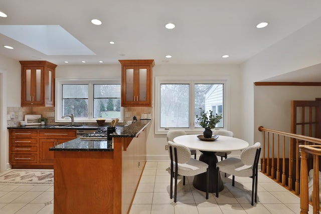 kitchen with plenty of natural light, tasteful backsplash, brown cabinetry, and a sink