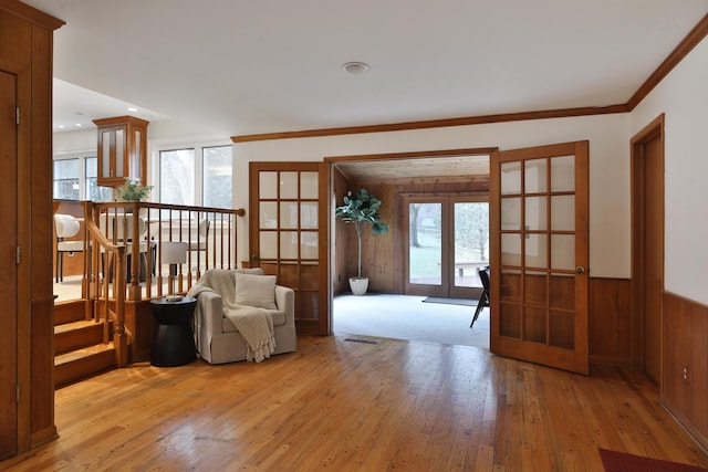 unfurnished room featuring light wood-type flooring, wainscoting, a healthy amount of sunlight, and crown molding