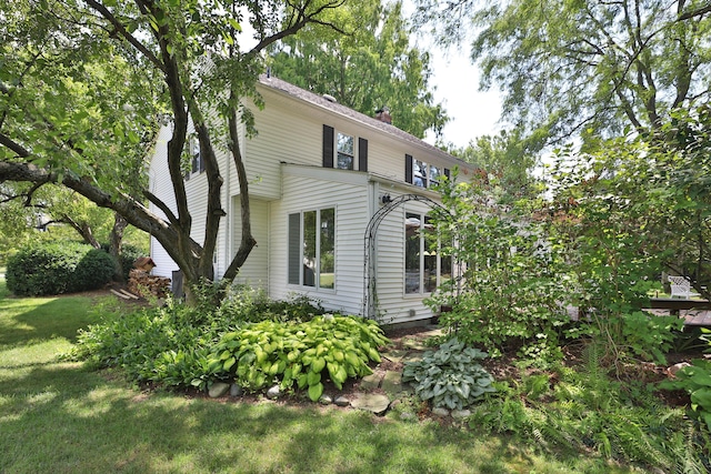 view of home's exterior featuring a lawn and a chimney