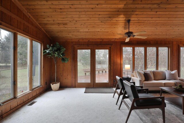 carpeted living area featuring vaulted ceiling, wood ceiling, visible vents, and wooden walls