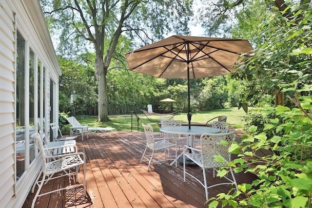 deck with outdoor dining area and a yard