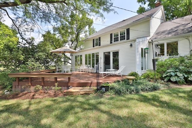 rear view of house with a lawn, a chimney, and a wooden deck