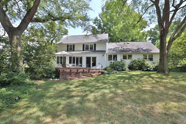 back of house featuring a lawn, a chimney, and a wooden deck